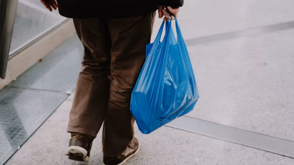 Photo of a man using a plastic bag to carry goods
