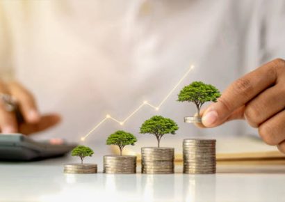 A businessman holding a coin with a tree that grows and a tree that grows on a pile of money. The idea of maximizing the profit from the business investment.